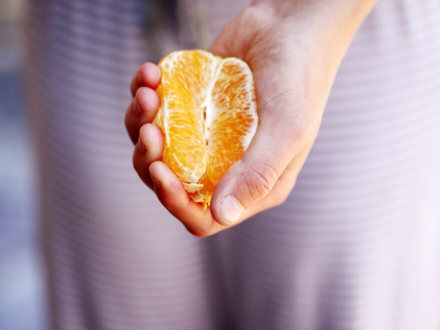 selective focus photography of person squeezing orange fruit